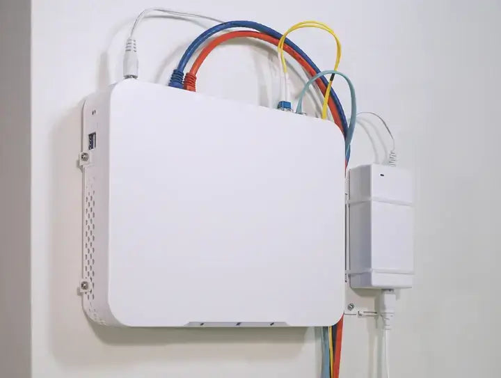 Netgate 4200/6100 Wandmontage-Kit installierter Router mit farbigen Kabeln an einer Wand.